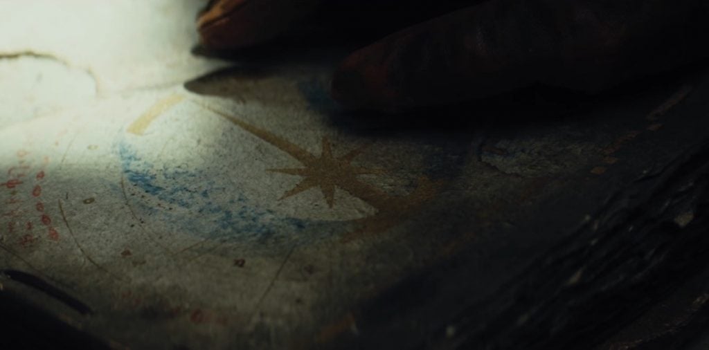 A hand touches a book bearing the symbol of the Jedi Order