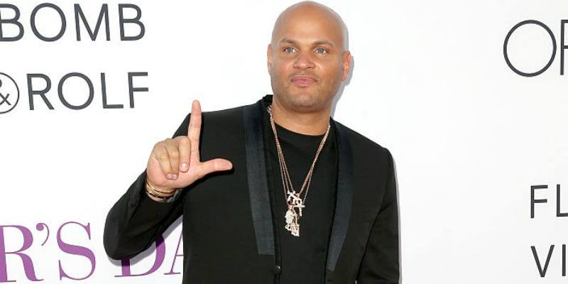 Stephen Belafonte has his thumb and finger up in an "L" shape on the red carpet.