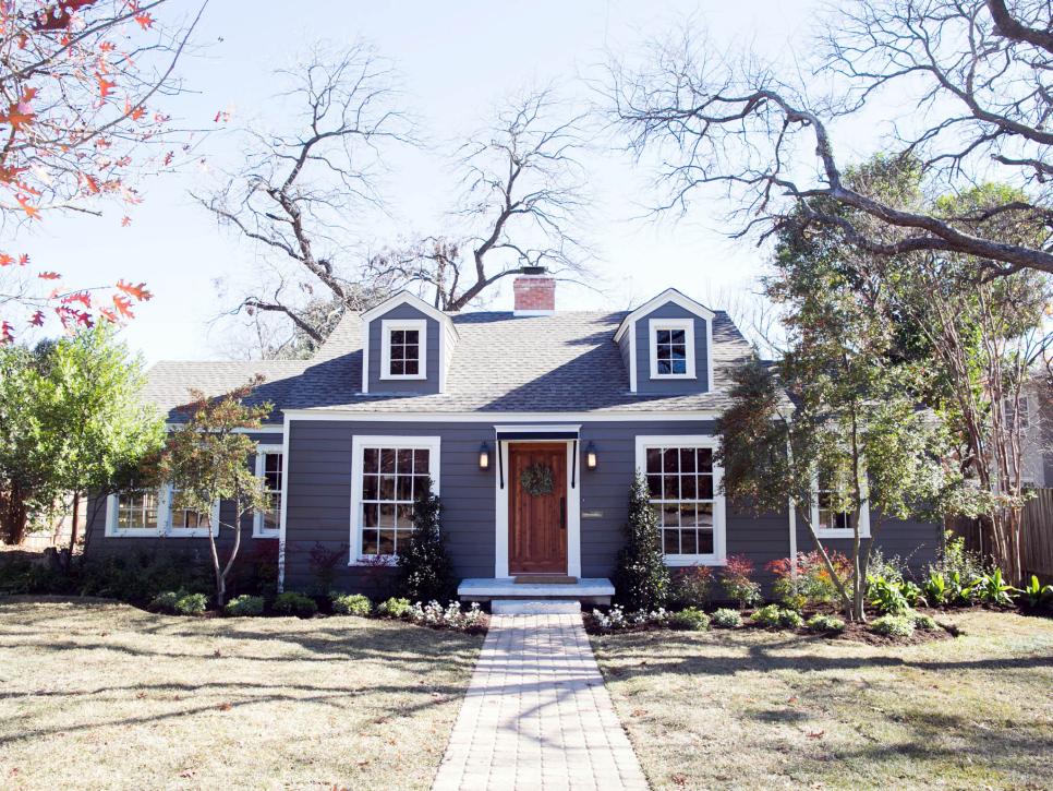 The exterior of this home features added dormers, a new front door, brick walkway, and fresh landscaping, as seen on Fixer Upper.