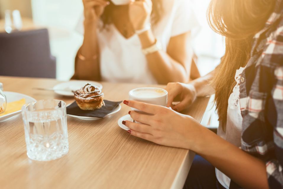 A woman speaks while the other is drinking