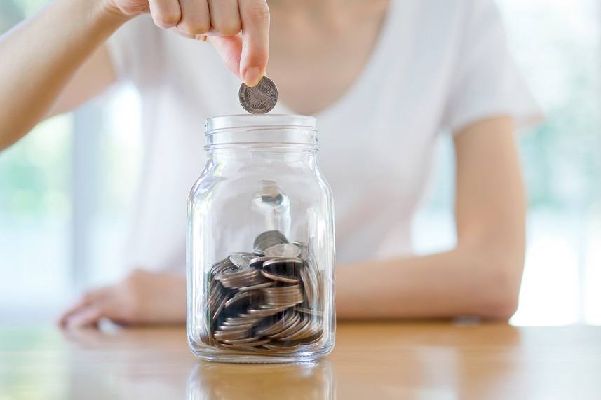 woman drops coins into a jar