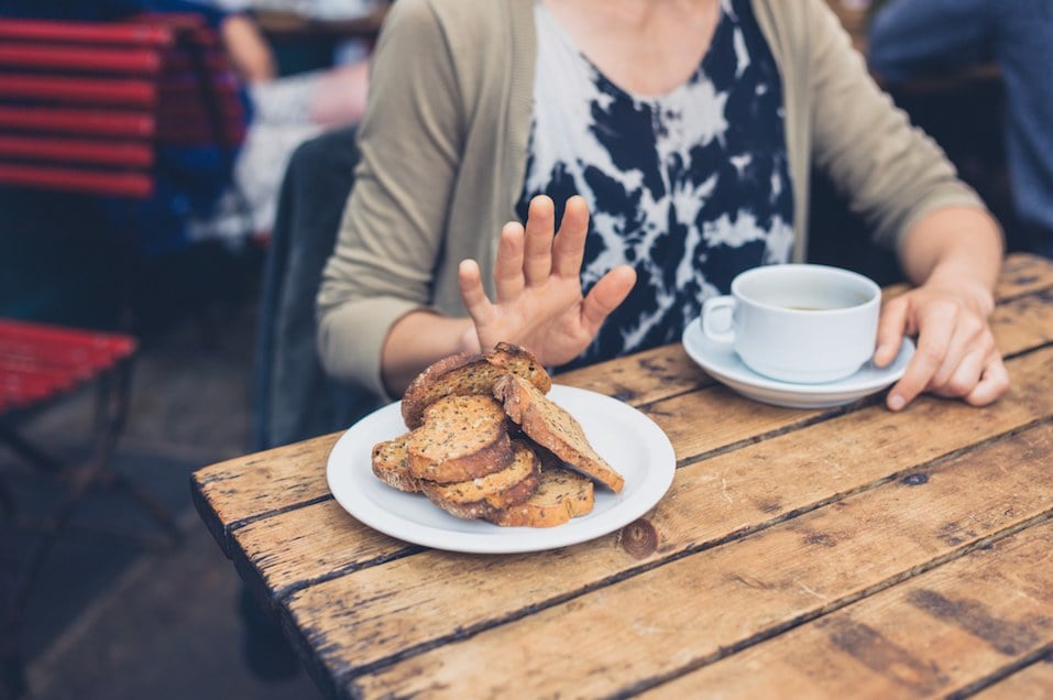 woman holding up her hand when offered a plate of toast