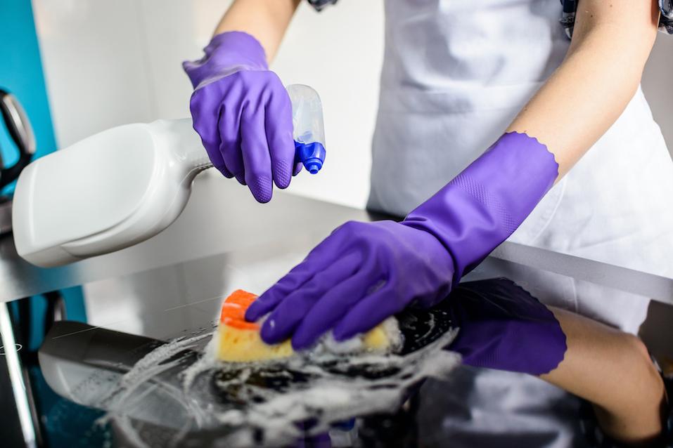 Woman cleaning kitchen top in rubber protective gloves