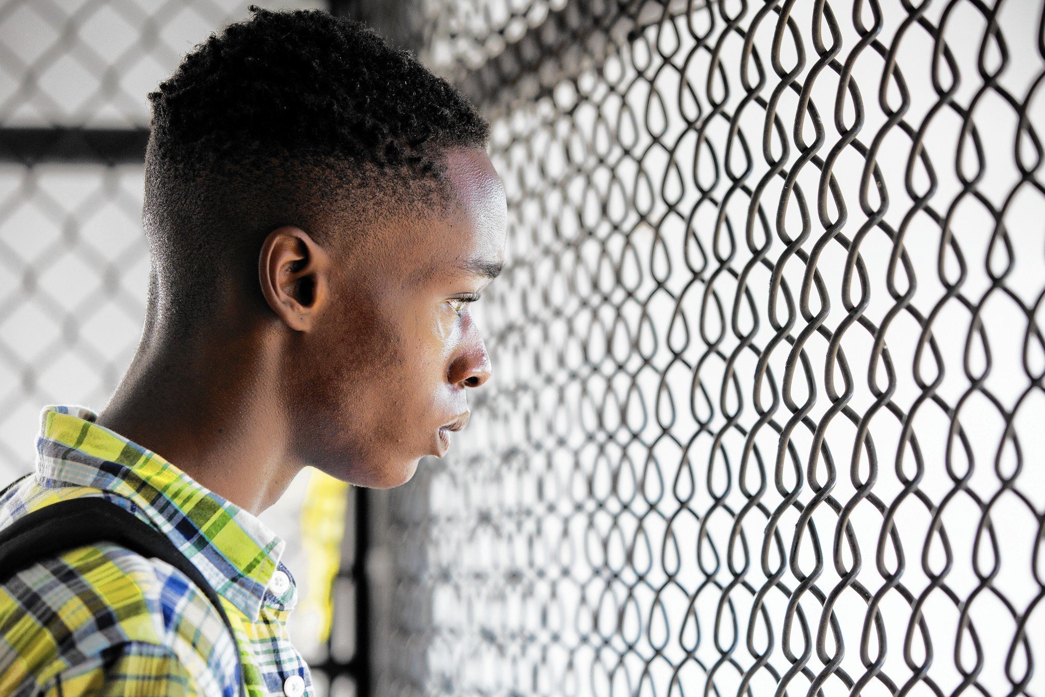 Chiron, as a teenager, stares through a fence in a scene from 'Moonlight.'