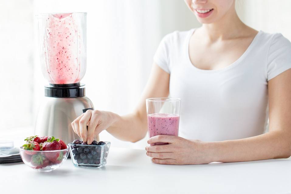 woman with blender, smoothie, and berries
