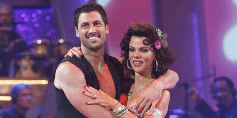 Debi Mazar and Maksim Chmerkovskiy have their arms around each other while listening to the judges.