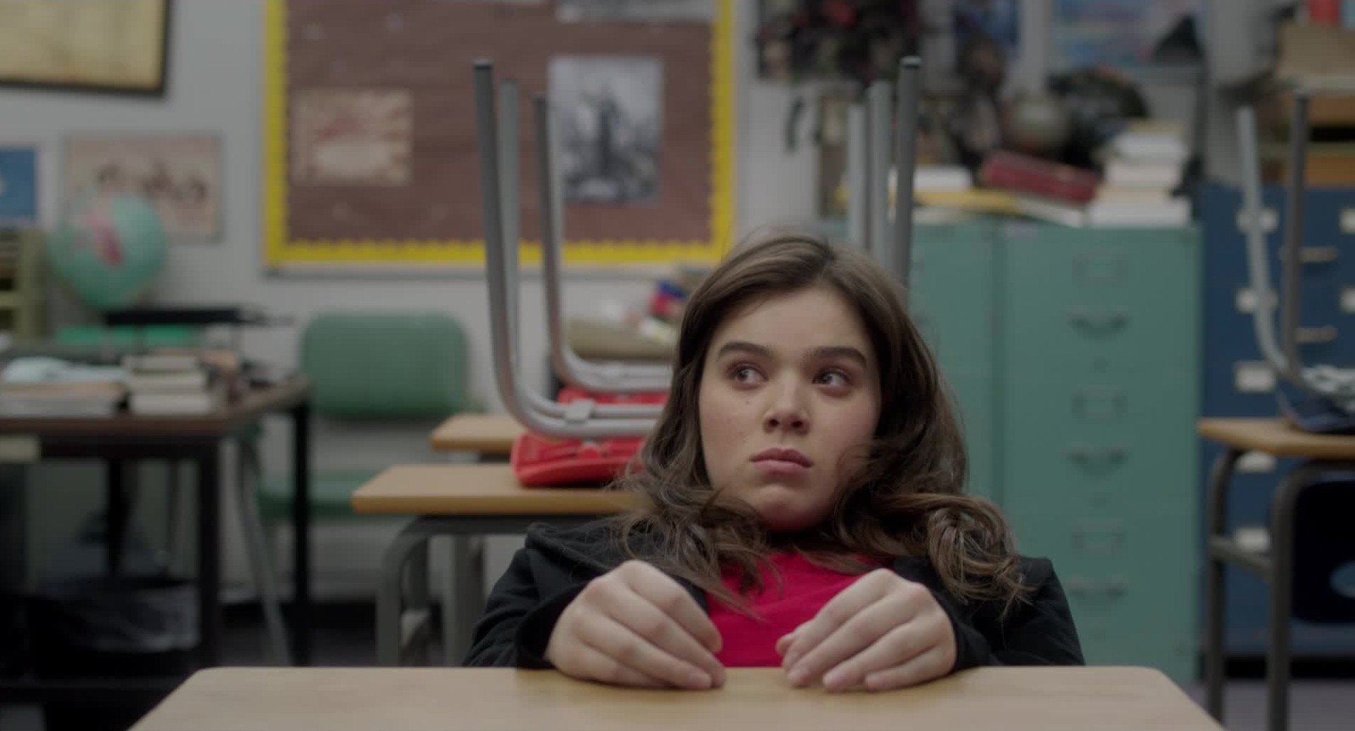 Nadine looks annoyed as she slouches in a school desk in a scene from 'The Edge of Seventeen.'