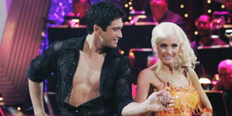 Dmitry Chaplin is holding Holly Madison's hand and is looking at her while dancing.