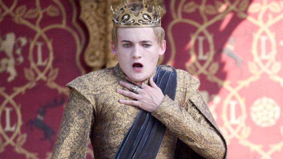 King Joffrey at his wedding with his arm up to his throat choking