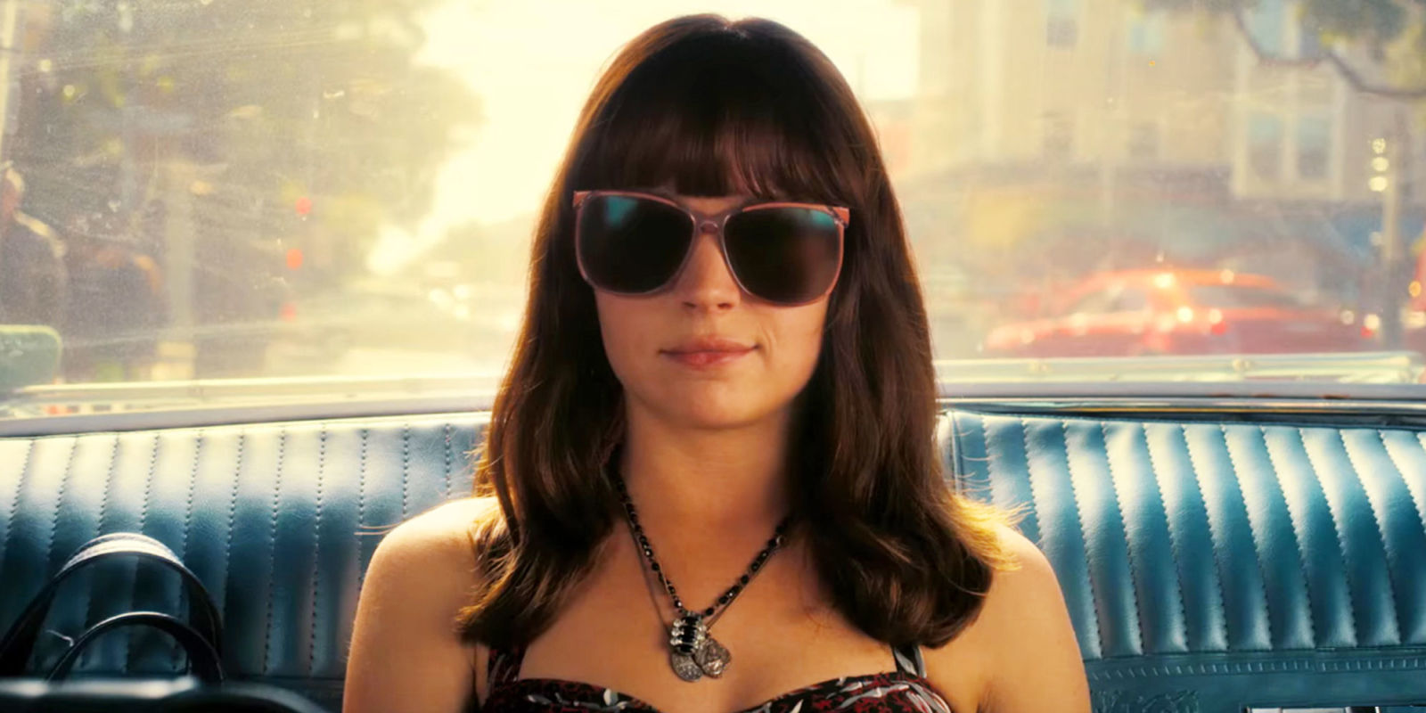 Britt Robertson sits in the back of a car while wearing sunglasses in a scene from Girlboss