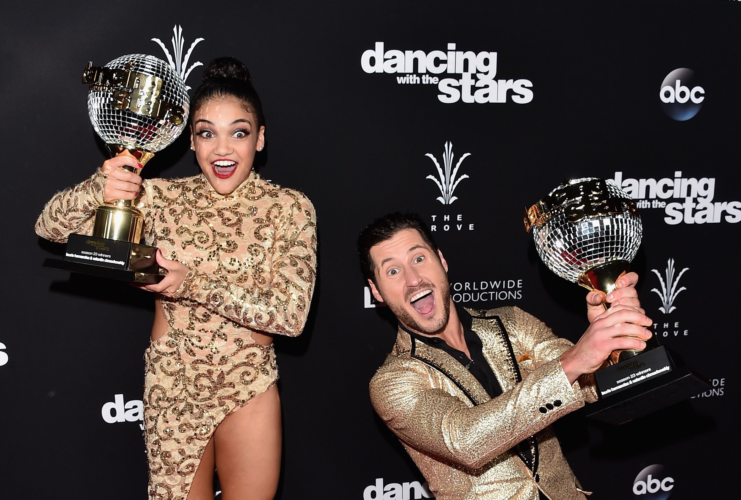 Laurie Hernandez and Val Chmerkovskiy stand on the red carpet and hold their mirror ball trophies after winning 'Dancing With the Stars.'