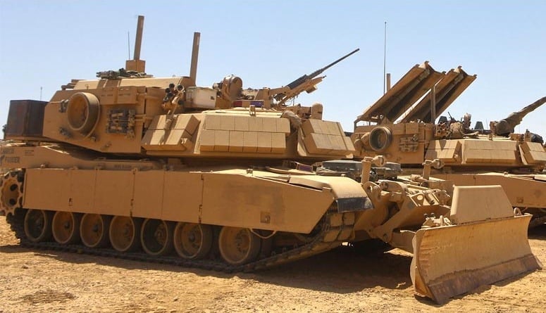 An M! Assault Breacher Vehicle parked in the sand.