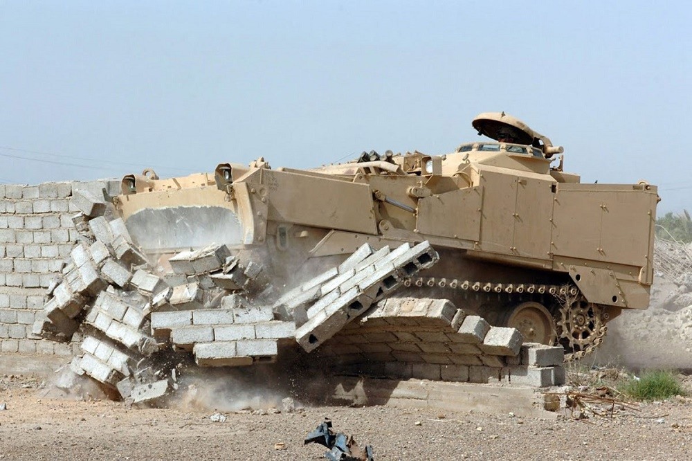 An M9 Armored Combat Earthmover plows through a wall.