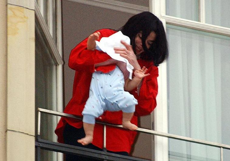 Michael Jackson holding his baby over a balcony