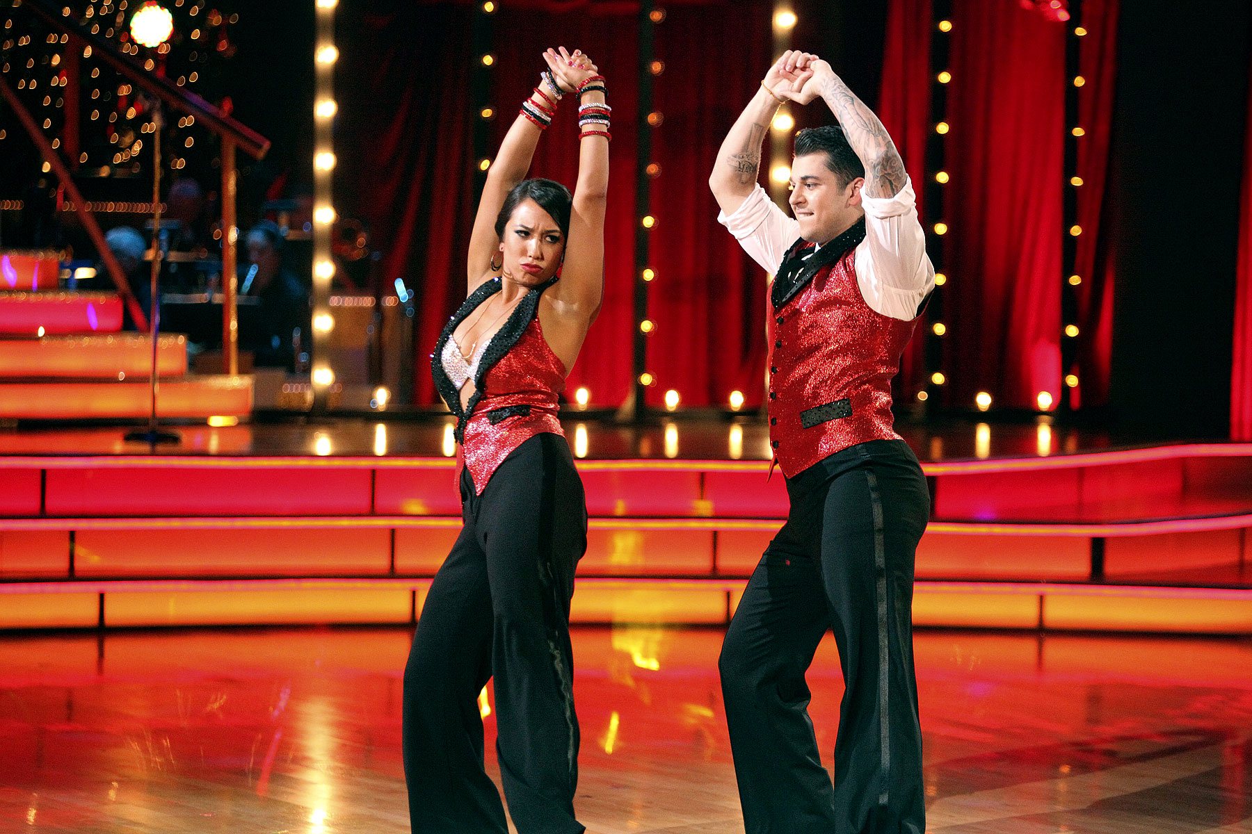 Cheryl Burke and Rob Kardashian wear matching glittery red vests as they dance with their arms in the air on 'Dancing With the Stars.'