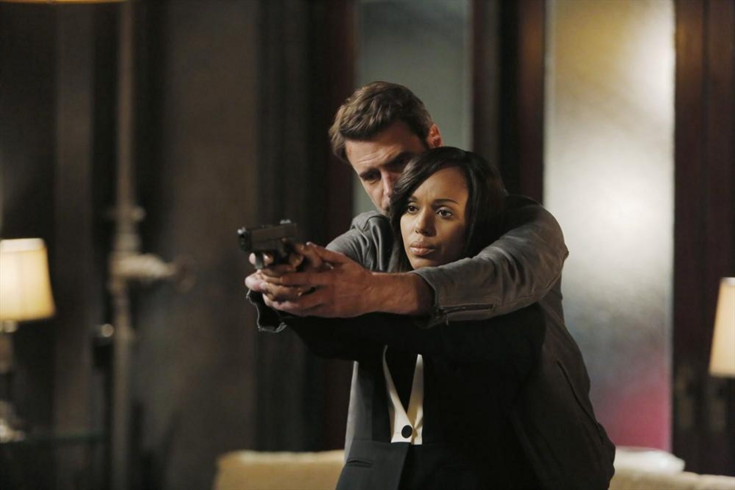 Jake teaches a weary-looking Olivia how to hold a gun in a scene from 'Scandal.'