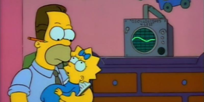 Homer Simpson is holding Lisa and is sitting next to a baby translator device.