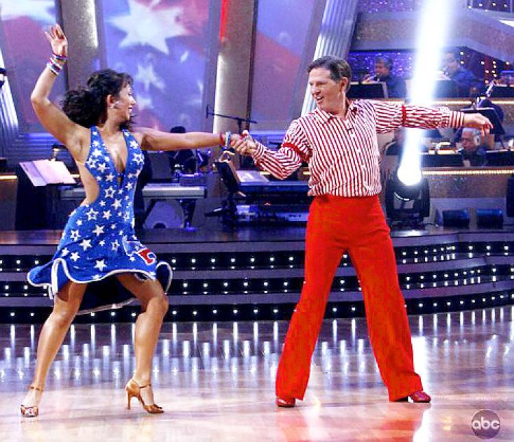 Cheryl Burke wears a blue dress with white stars and Tom Delay wears a red and white striped outfit as they dance on 'Dancing With the Stars.'