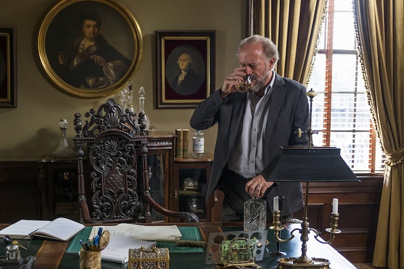 Gregory drinks as he stands in front of his desk in a scene from 'The Walking Dead's seventh season.
