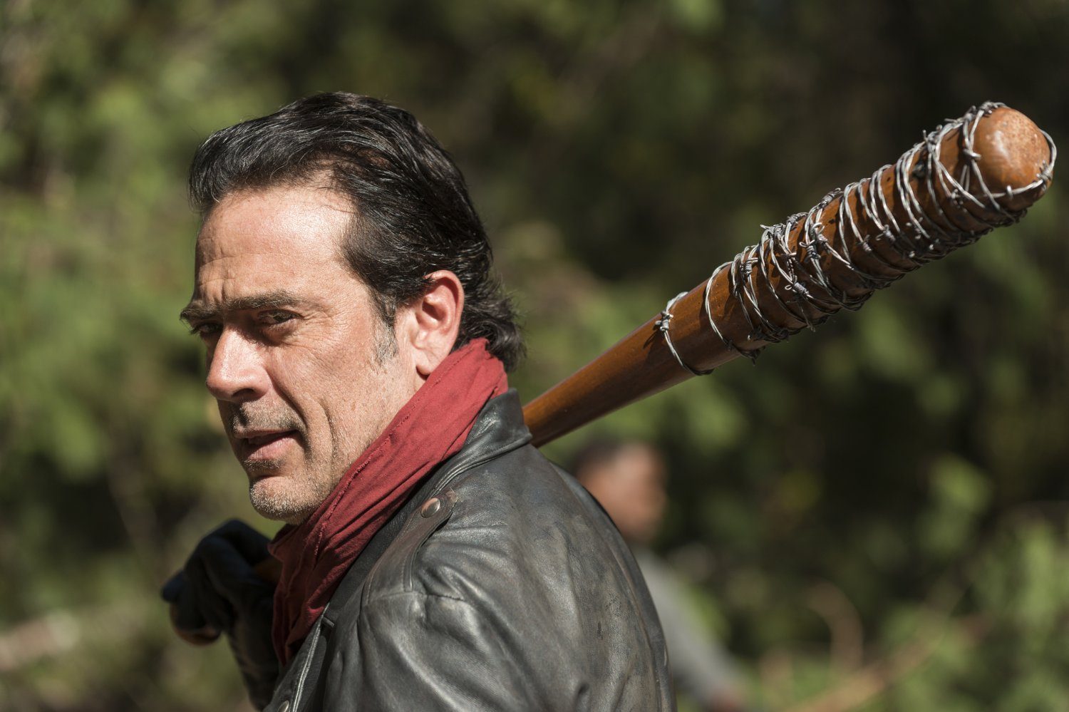 Negan, wearing a red scarf, with a barbed-wire baseball bat on his shoulder