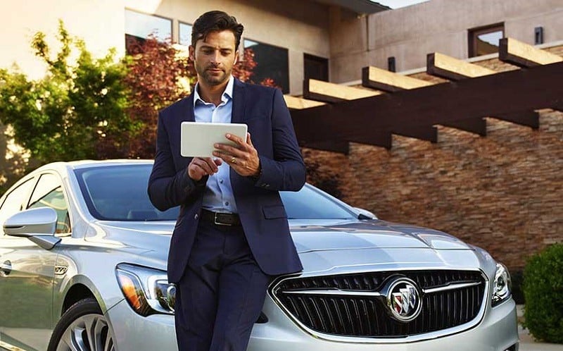 View of man holding tablet while leaning on 2017 Buick LaCrosse