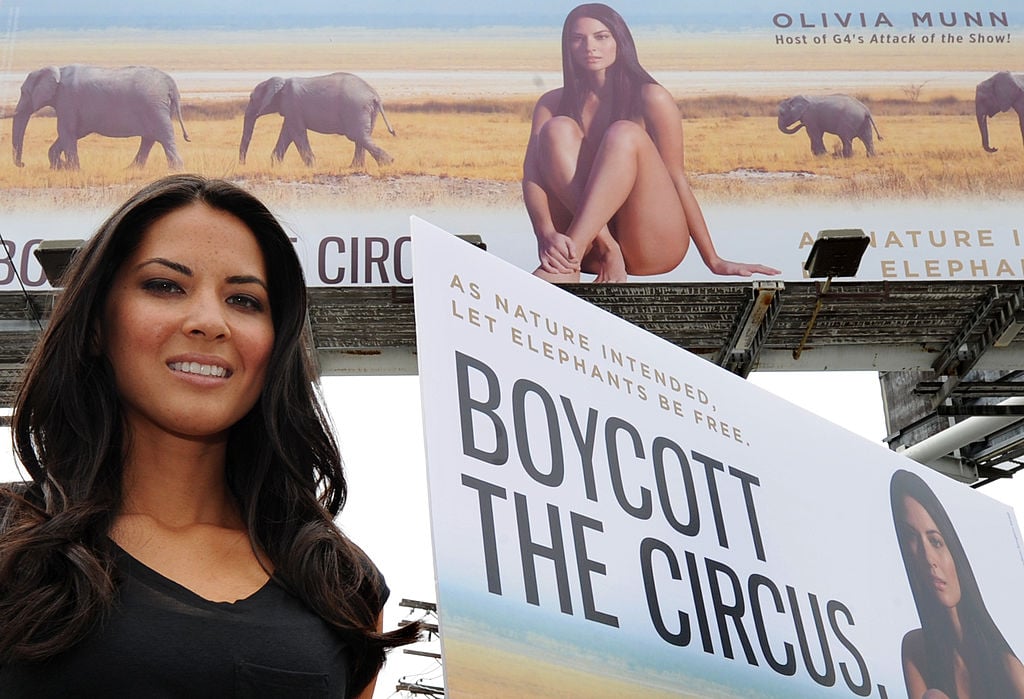 Actress Olivia Munn beside her billboard that says "boycott the circus"