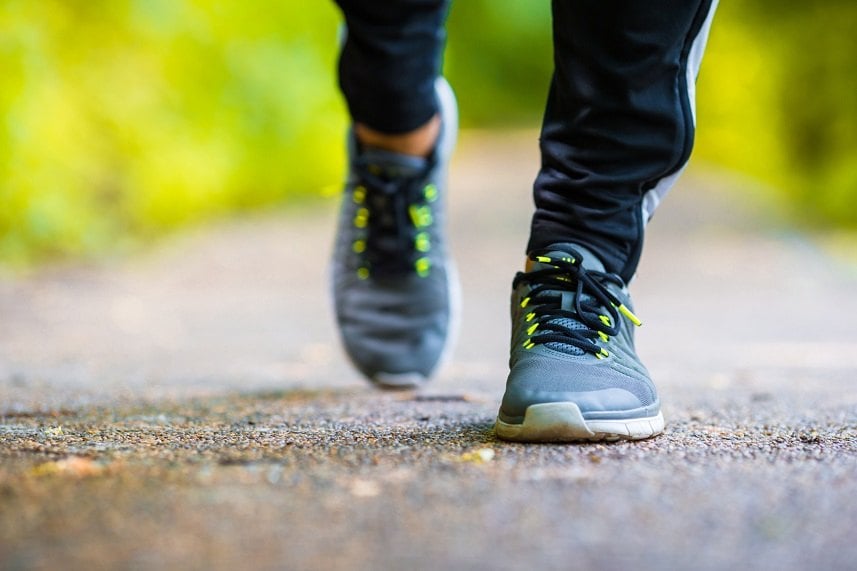 person in running shoes walking on paved path