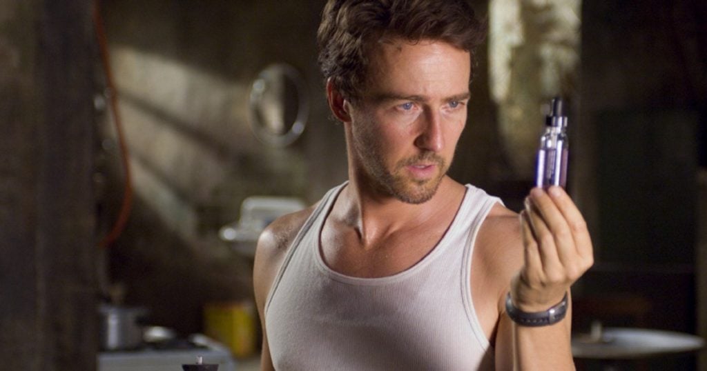 Ed Norton as Bruce Banner, wearing a white tank top and looking at a purple vial in his hand
