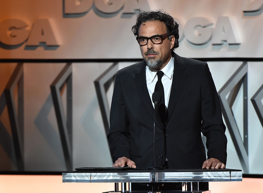 Alejandro Gonzalez Inarritu speaking at a podium, wearing a suit