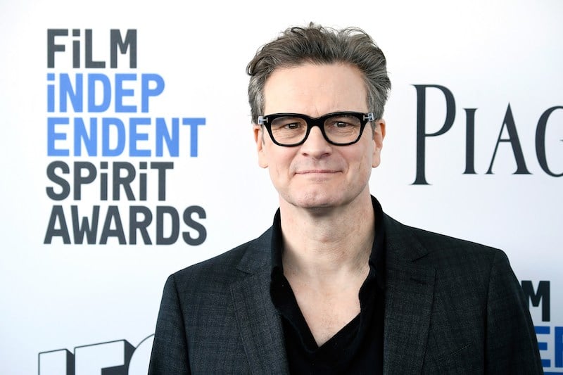 Colin Firth wears glasses and a black suit while posing on the carpet for the Film Independent Spirit awards