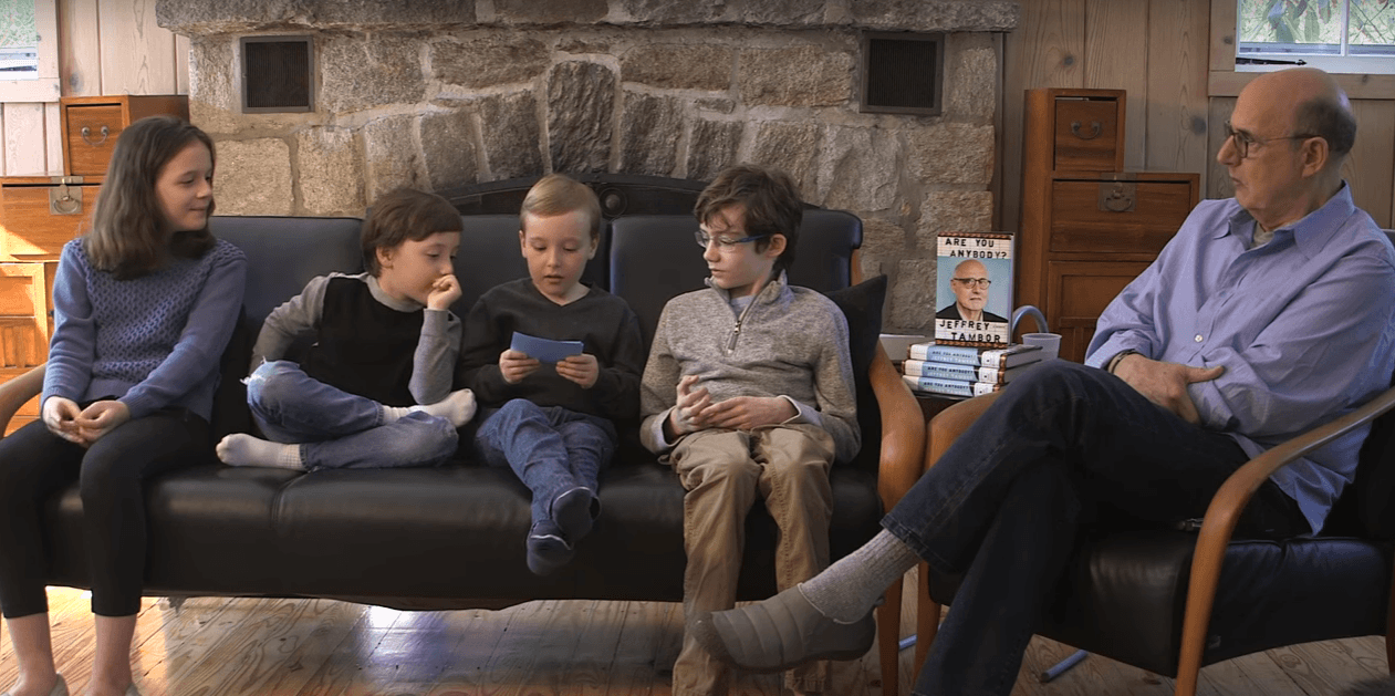 Jeffrey Tambor sits in a chair next to his new book and his four young children