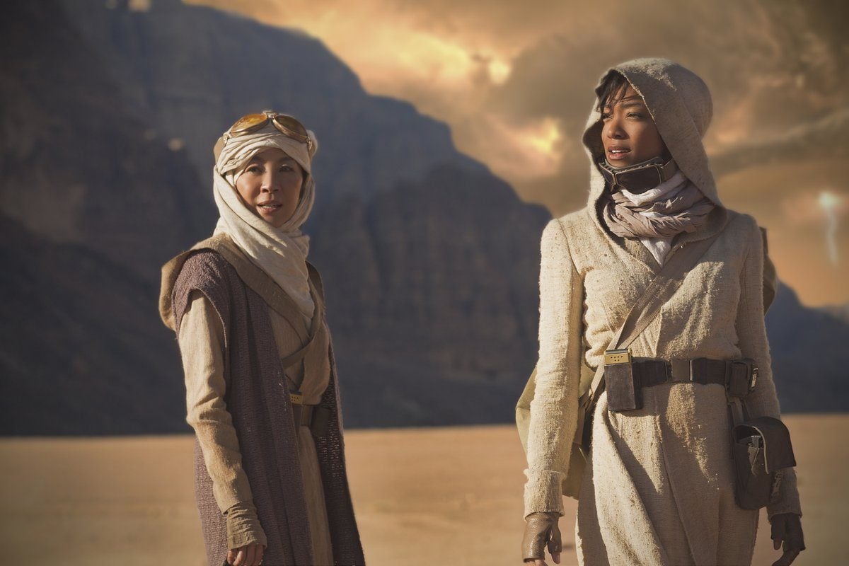 Sonequa Martin-Green as First Officer Michael Burnham and Michelle Yeoh as Captain Philippa Georgiou stand in a desert landscape dressed in robes.