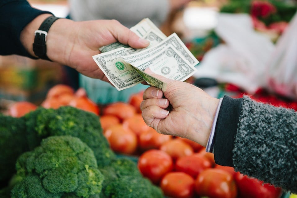 Woman pays for fresh produce at local farmers market