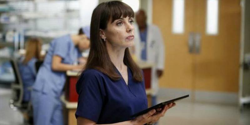 Constance Zimmer is in blue scrubs and is holding a tablet.