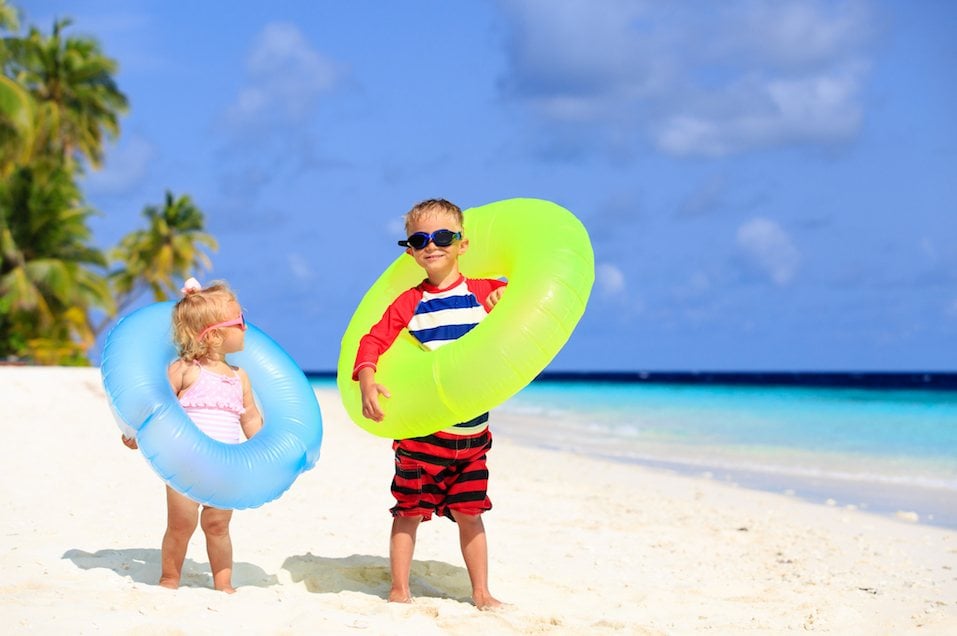 little boy and toddler girl play on tropical beach