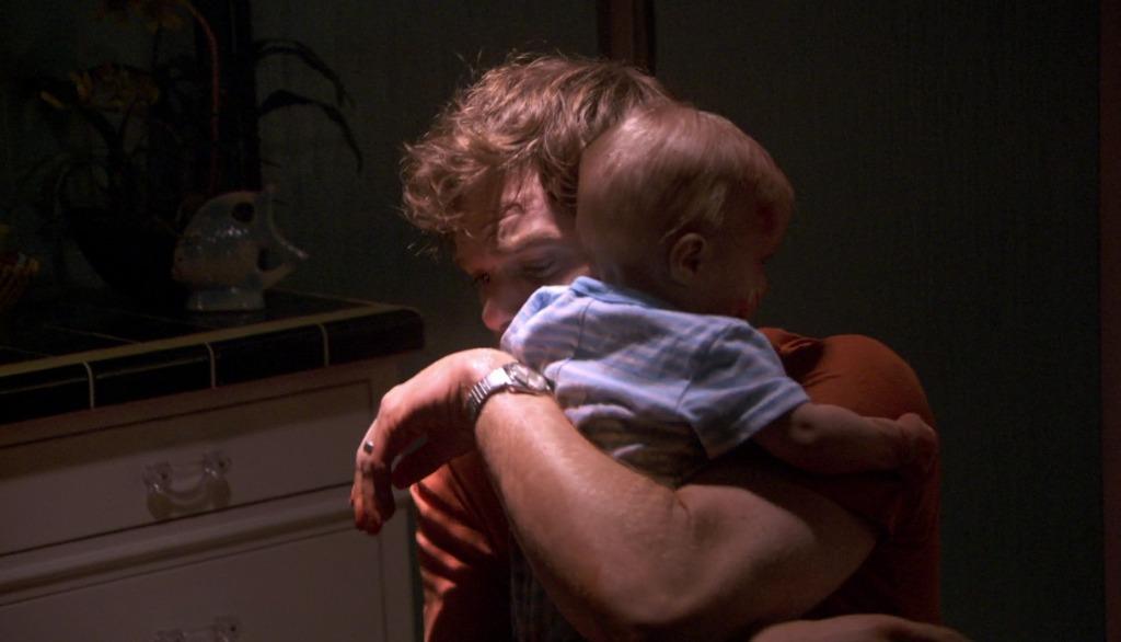 Michael C. Hall as Dexter Morgan holding his son Harrison covered in blood