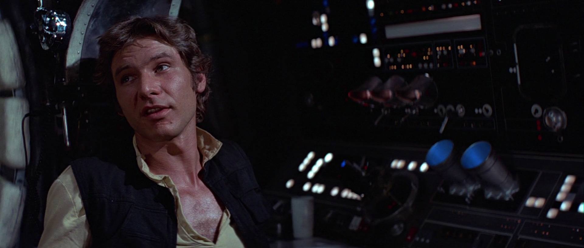 Han Solo sitting in a chair with his feet up, looking to the left of the frame and speaking
