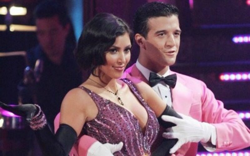 Kim Kardashian and Mark Ballas pose together in purple and pink outfits as they dance.