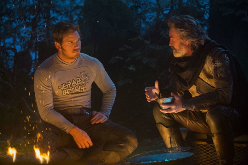 Chris Pratt and Kurt Russell sitting around a campfire and talking