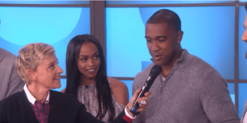 Ellen is holding a microphone to Will G's face and Rachel Lindsay is next to him looking at him.