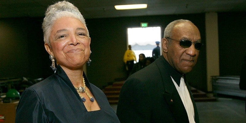 Bill and Camille Cosby are walking next to each other.