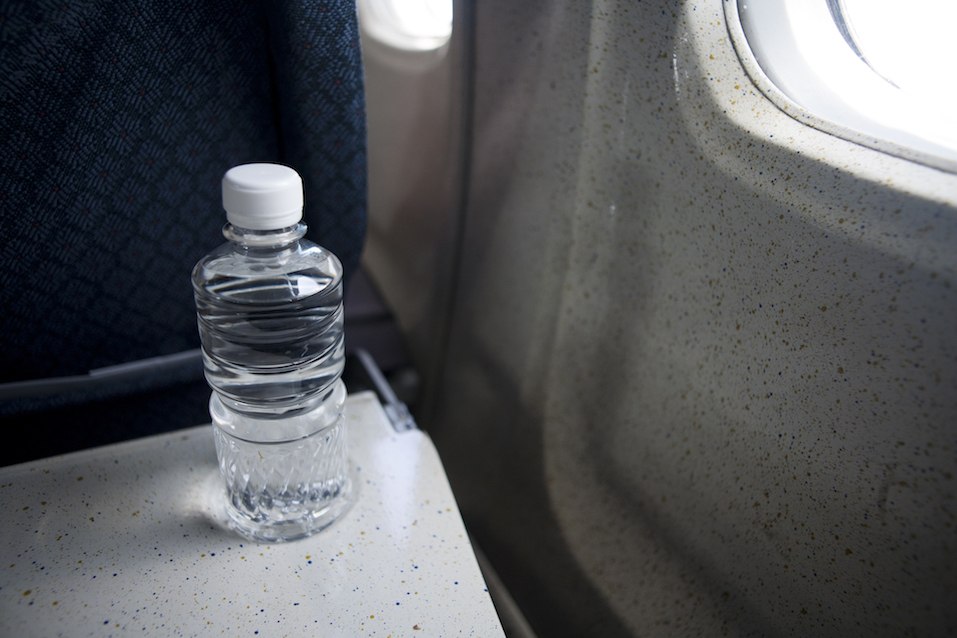 unopened bottle of water on a tray table in airplane