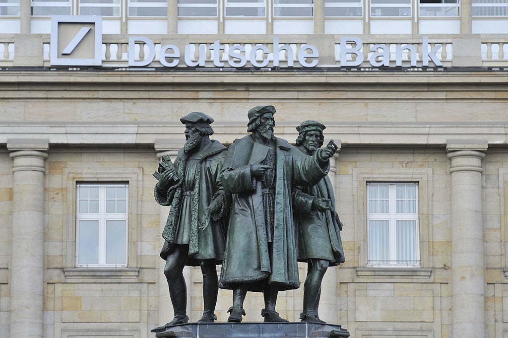 Statues forming the Gutenberg memorial stand in front of a Deutsche Bank building in Frankfurt