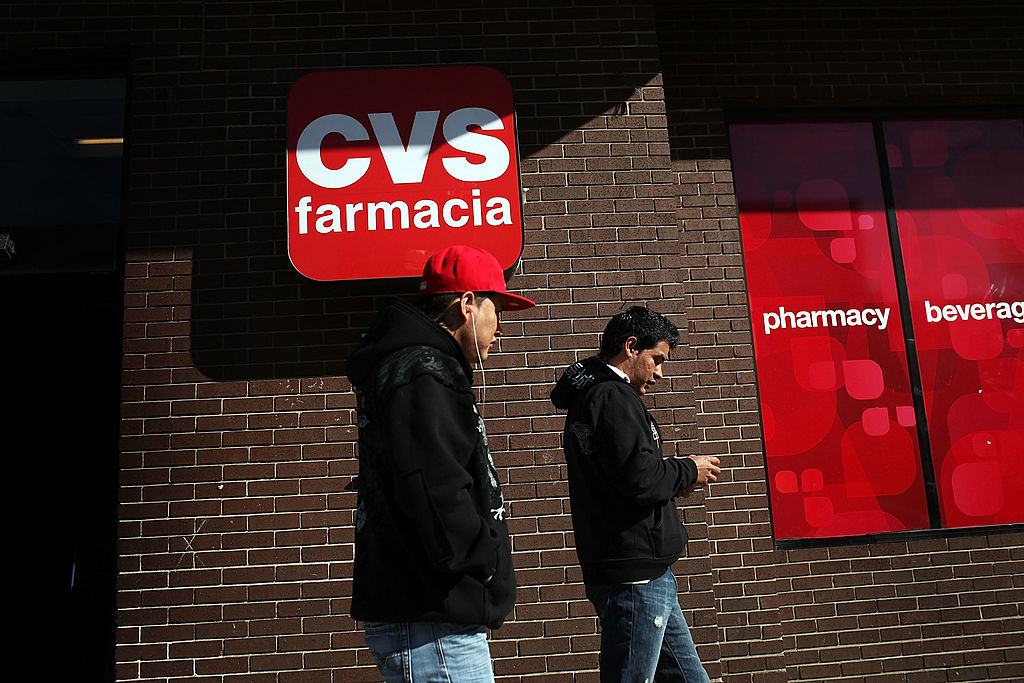 Two men walk by a bilingual sign for a CVS pharmacy in New Jersey