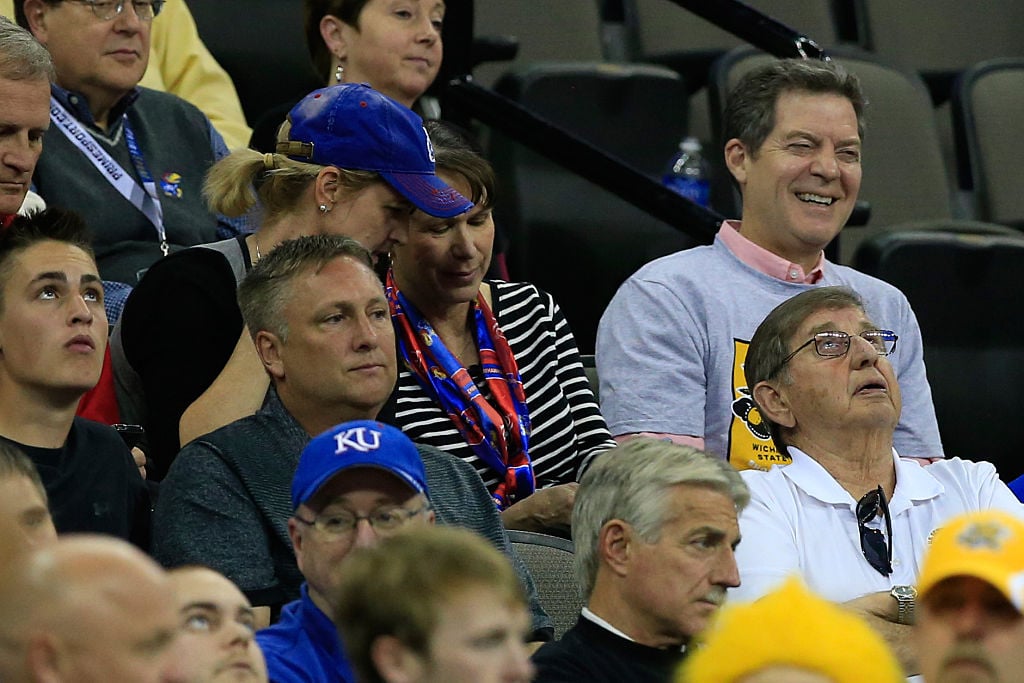 Sam Brownback enjoys a college basketball game while his constituents stick through it