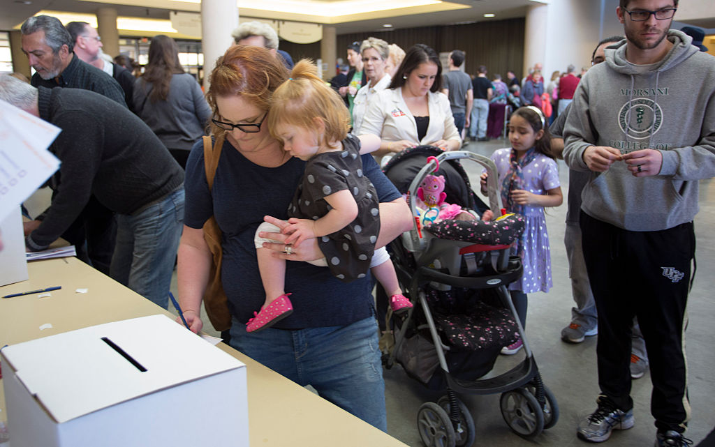 A woman holds her baby as she votes during the state's Republican caucus in Wichita, Kansas