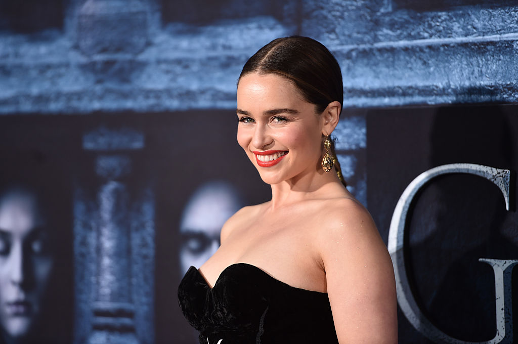 Emilia Clarke posing in front of a 'Game of Thrones' poster