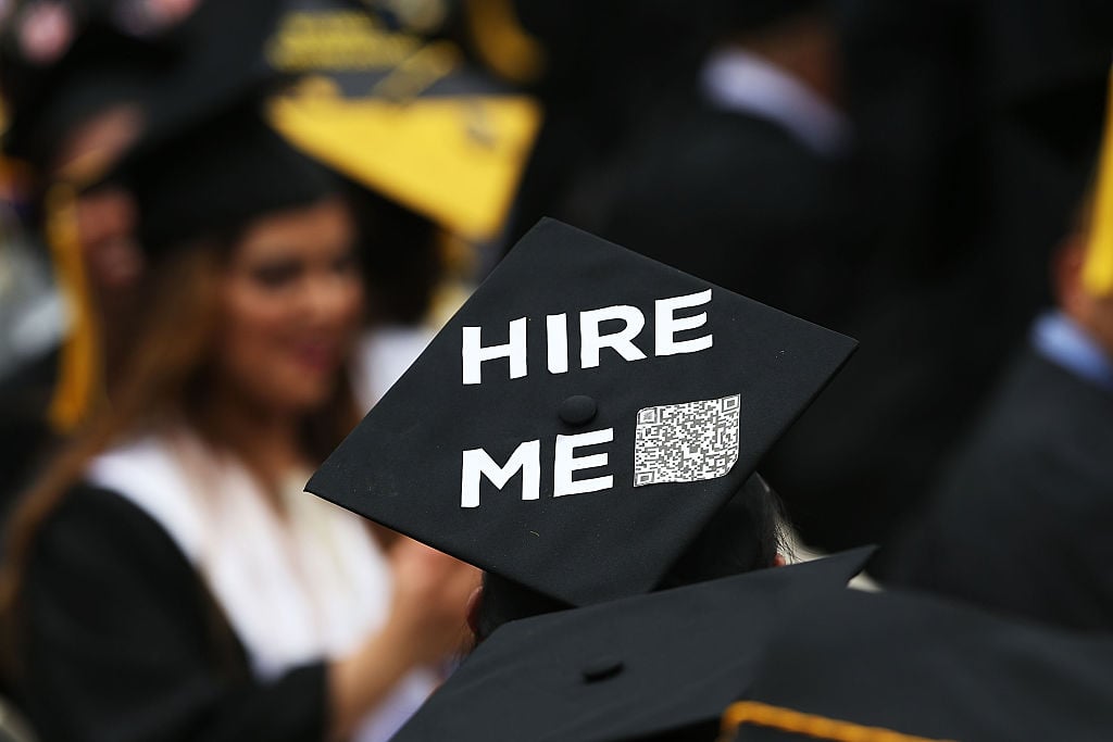 A graduating student's cap says "hire me," expressing concerns about paying off college tuition in coming years