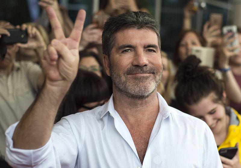 Simon Cowell flashes the peace sign for cameras