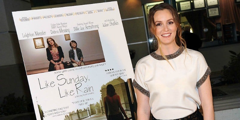 Leighton Meester is smiling next to a movie poster.